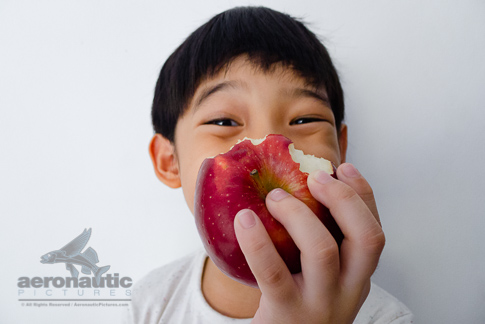 Food Stock Photo - A Happy Kid Holding a Half-eaten Apple - Download Royalty Free