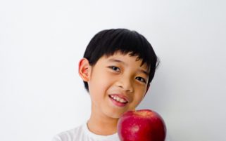Food Stock Photo - A Healthy Kid Smiling Happily While Holding an Apple Download Royalty Free!