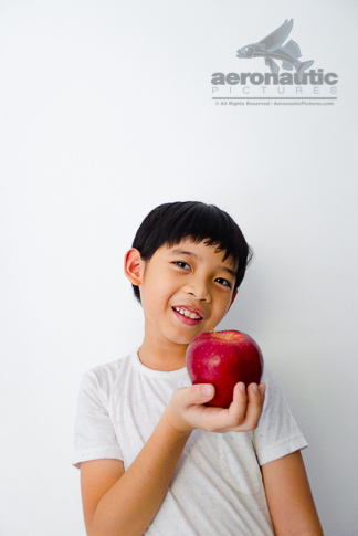 Food Stock Photo - A Healthy Kid Smiling Happily While Holding an Apple Download Royalty Free!