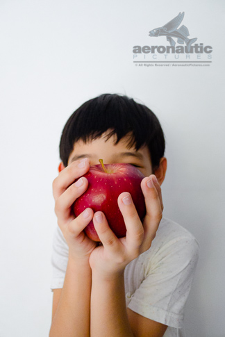 Food Stock Photo - A Kid Covering His Face Playfully with an Apple Download