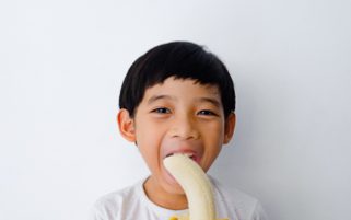 Food Stock Photo - A Kid Eating a Banana - Download Royalty Free!