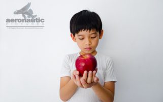 Food Stock Photo - A Kid Holding an Apple in Front of Him - Download Royalty Free