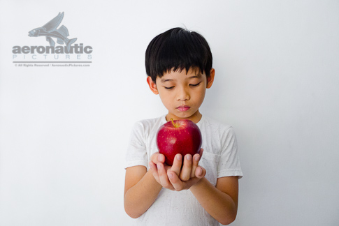 Food Stock Photo - A Kid Holding an Apple in Front of Him - Download Royalty Free