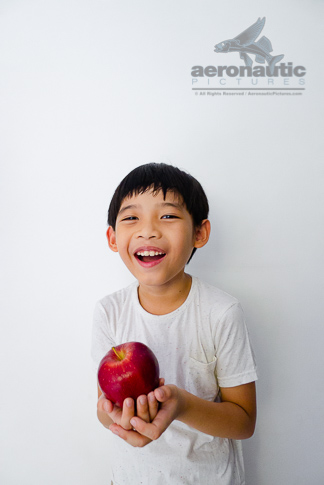 Food Stock Photo - A Kid Holding an Apple, Laughing Happily - Download Royalty Free