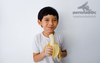 Food Stock Photo - A Kid Looking Happy While Eating a Banana Download