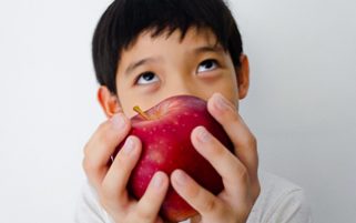 Food Stock Photo - A Kid Thinking and Holding an Apple Download Royalty Free